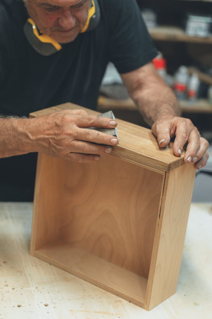 Handarbeit beim Schleifen eines Holzmöbels